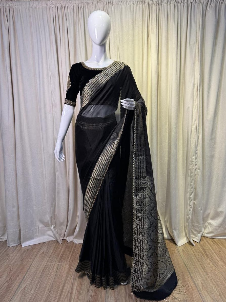 Black saree with gold border on a mannequin against a white curtain background